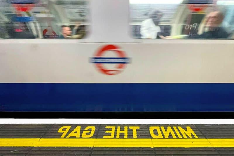 A blurry image of a moving train through the London tube. The words 'mind the gap' are on the sidewalk